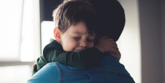 Little boy in green shirt hugging dad in blue shirt