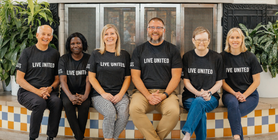Group of people sitting together in LIVE UNITED t-shirts
