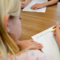 young girl student sitting at her desk with a pencil in her hand writing on a piece of paper