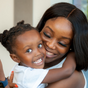 Smiling African American woman, Rose, hugging her smiling young boy